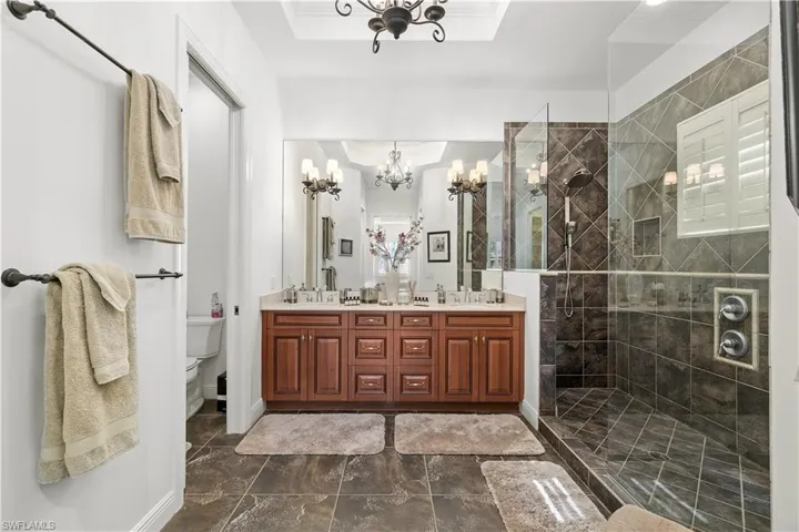 Bathroom featuring walk in shower, suspended lighting, and double vanity