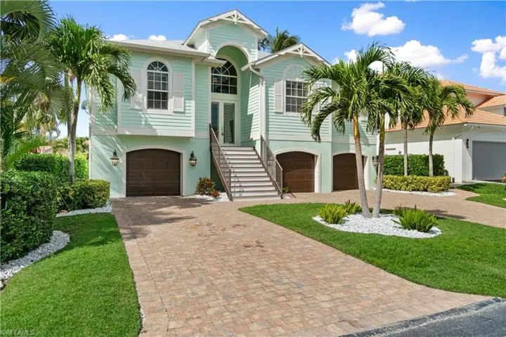 Coastal inspired home with a garage, decorative driveway, and stucco siding