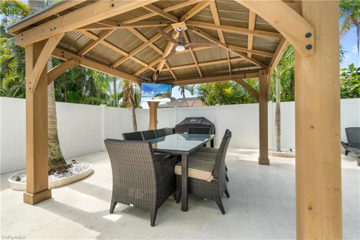 Fenced backyard with a gazebo, outdoor dining area, a patio area, and a grill