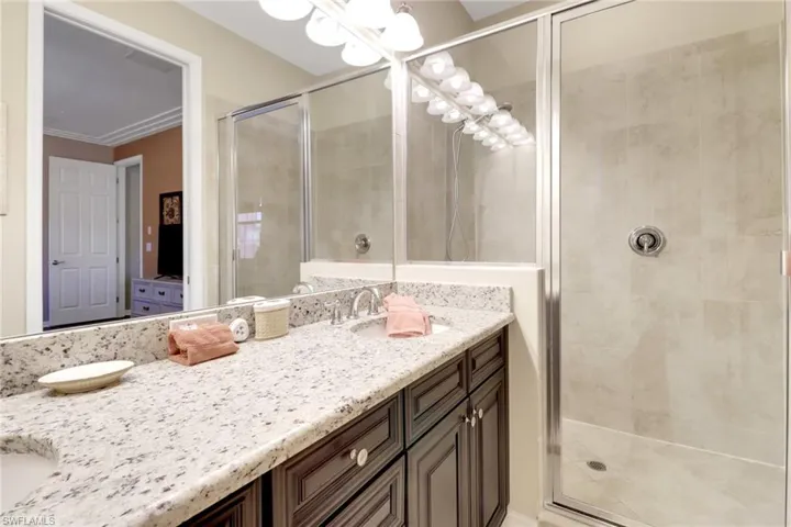 Full bath with a sink, a shower stall, an inviting chandelier, and double vanity