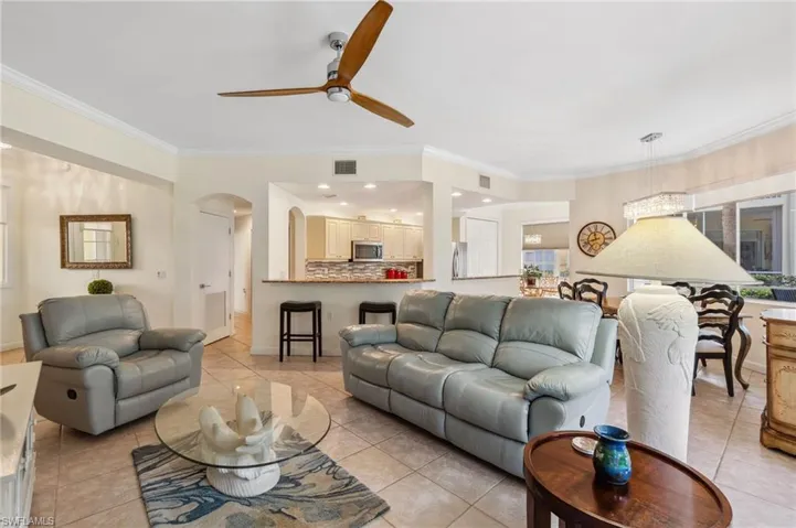 Living room with ceiling fan, ornamental molding, and light tile patterned flooring