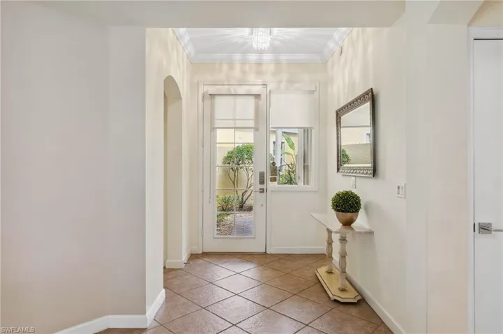 Doorway to outside featuring crown molding and light tile patterned floors