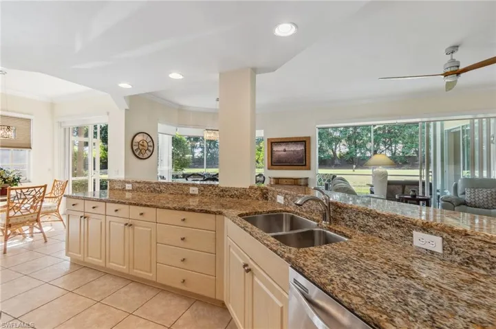 Kitchen featuring crown molding, sink, ceiling fan, light tile patterned floors, and stone countertops