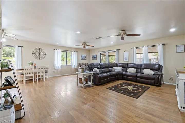 Living room featuring a ceiling fan, light wood-type flooring, baseboards, visible vents, and recessed lighting