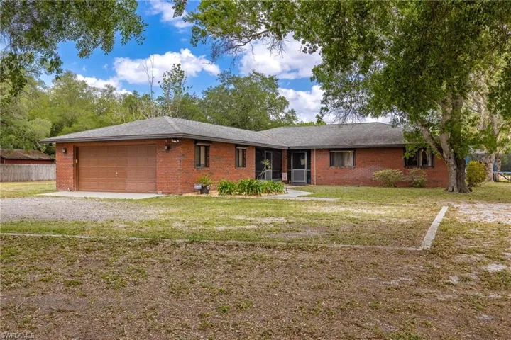 Ranch-style house with brick siding, driveway, a front lawn, and an attached garage