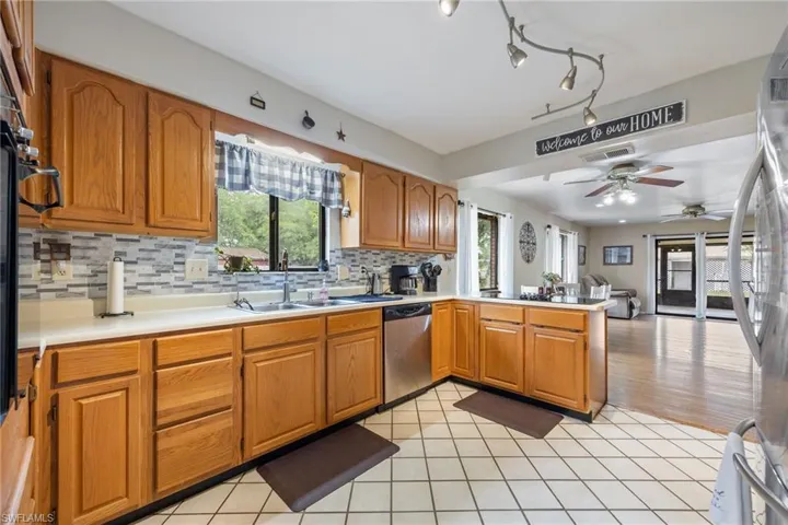 Kitchen with light countertops, a sink, a ceiling fan, a peninsula, and appliances with stainless steel finishes