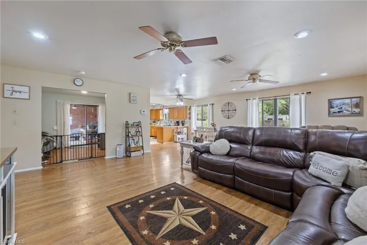 Living area featuring light wood-type flooring, baseboards, visible vents, ceiling fan, and recessed lighting
