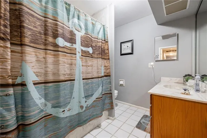 Guest Bathroom featuring tile patterned floors, toilet, vanity, a shower with curtain, and baseboards