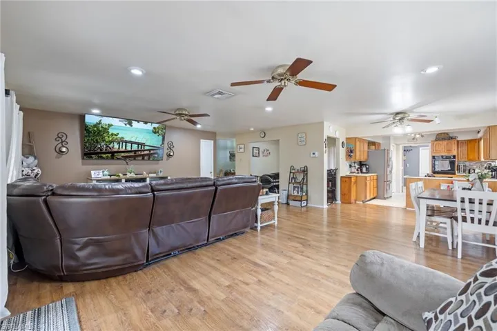 Living room with light wood-style flooring, visible vents, and ceiling fan