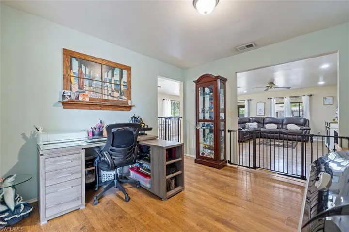 Home office featuring light wood-style flooring, baseboards, ceiling fan, and visible vents