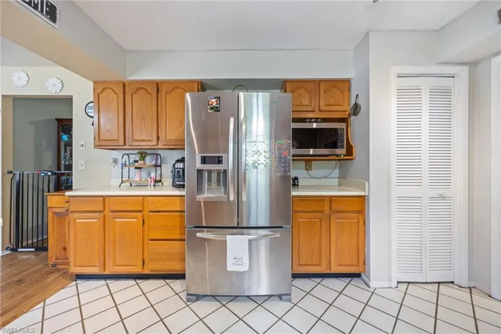 Kitchen with light tile patterned flooring, brown cabinets, light countertops, and appliances with stainless steel finishes