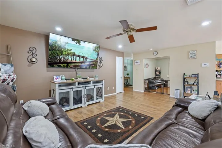 Living room with baseboards, wood finished floors, recessed lighting, and a ceiling fan