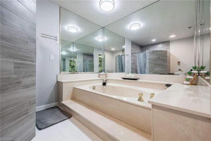 Main bathroom featuring tile patterned flooring, a stall shower, and a bath