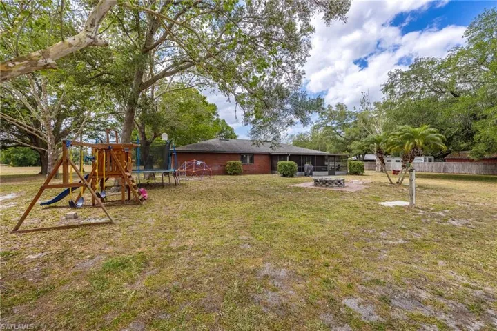 View of yard with a playground, a fire pit, and a trampoline