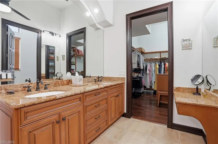 Full bath with double vanity, a walk in closet, ceiling fan, and light tile patterned floors