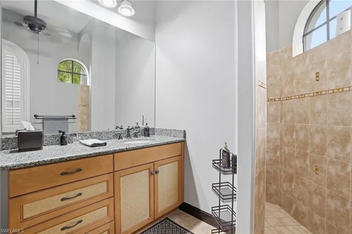 Bathroom featuring walk in shower, vanity, and ceiling fan