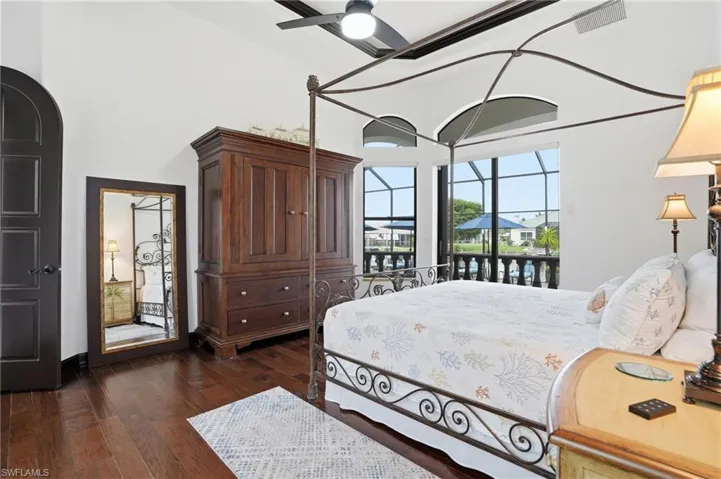 Bedroom with dark wood finished floors, ceiling fan, a high ceiling, and access to outside