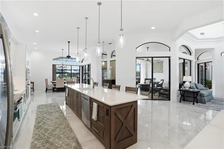 Kitchen featuring light stone counters, ornamental molding, a spacious island, open floor plan, and a breakfast bar