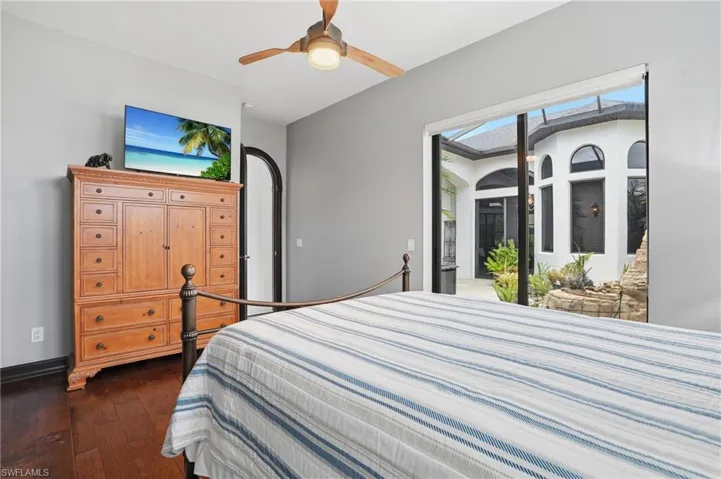 Bedroom featuring dark wood-style flooring, ceiling fan, access to outside, and multiple windows