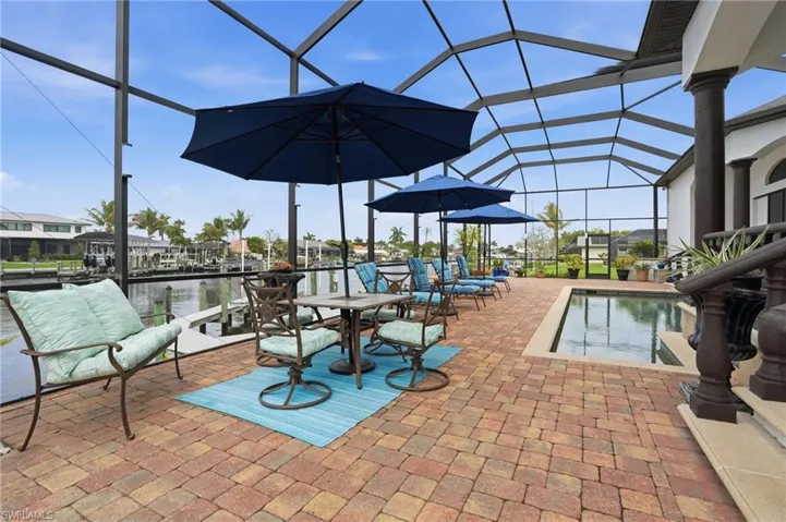 View of patio with a lanai, a sunroom, an outdoor pool, and a water view