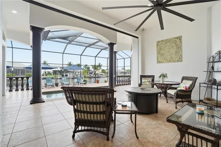 View of patio featuring a sunroom, glass enclosure, an outdoor pool, outdoor dining space, and a residential view