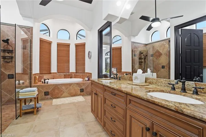 Full bath with ceiling fan, double vanity, a tile shower, a garden tub, and light tile patterned floors