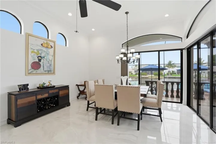 Dining area featuring hanging lights, crown molding, a ceiling fan, a water view, and light marble finish floors
