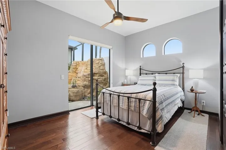 Bedroom featuring access to outside, dark wood-style floors, multiple windows, and a ceiling fan
