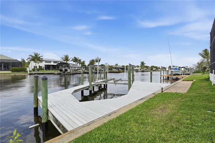 Dock area with boat lift, a lawn, a water view, and a residential view