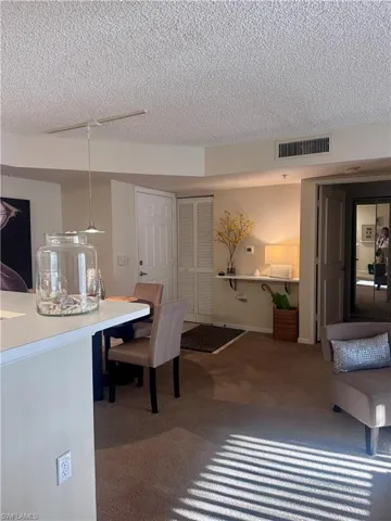 Dining room with a textured ceiling and dark colored carpet