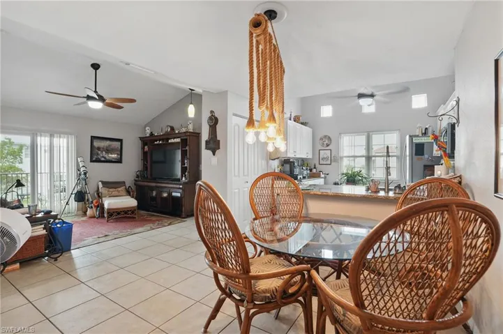 Dining area featuring a ceiling fan, vaulted ceiling, light tile patterned floors, and plenty of natural light