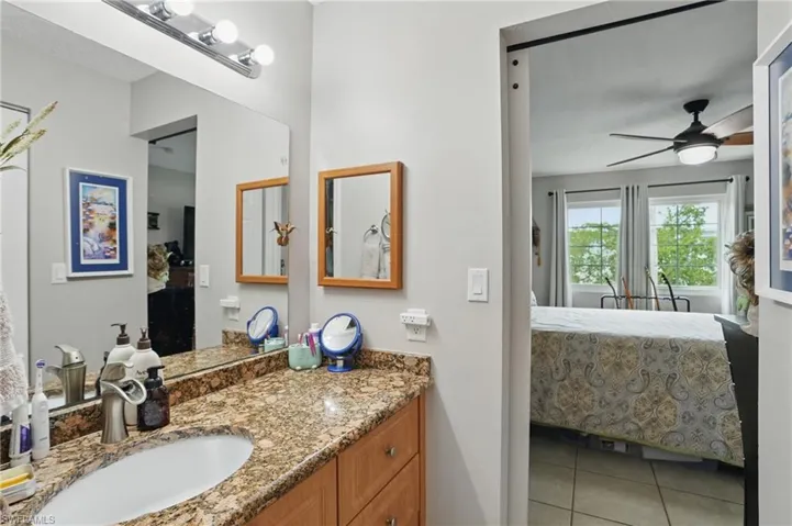 Ensuite bathroom featuring ceiling fan, tile patterned flooring, and vanity