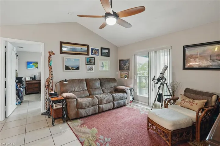 Living area with vaulted ceiling, a ceiling fan, and light tile patterned floors