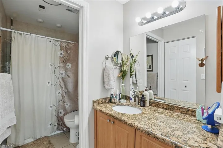 Bathroom with tile patterned floors, vanity, a shower with curtain, and a closet