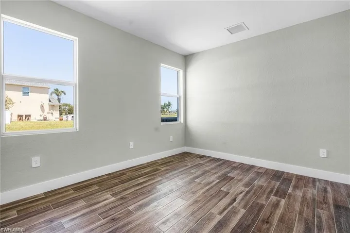 Spare room featuring a wealth of natural light and dark wood-type flooring