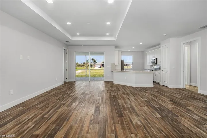 Unfurnished living room featuring a tray ceiling and dark hardwood / wood-style flooring
