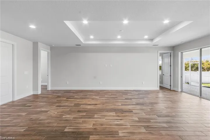 Empty room featuring a textured ceiling, a tray ceiling, and hardwood / wood-style flooring