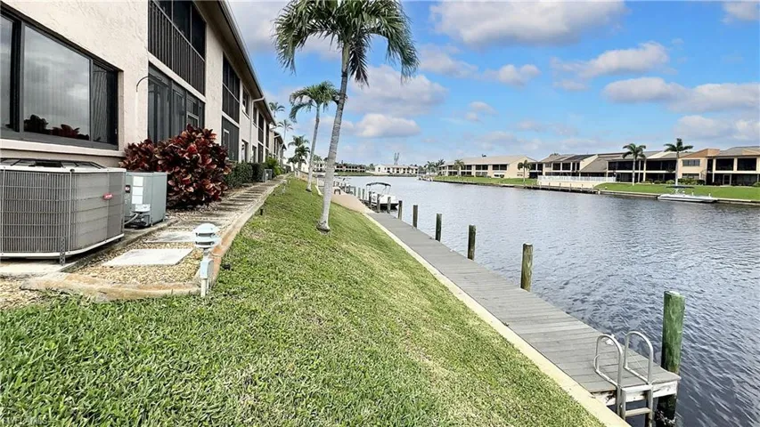 View of dock featuring central AC, a water view, and a yard