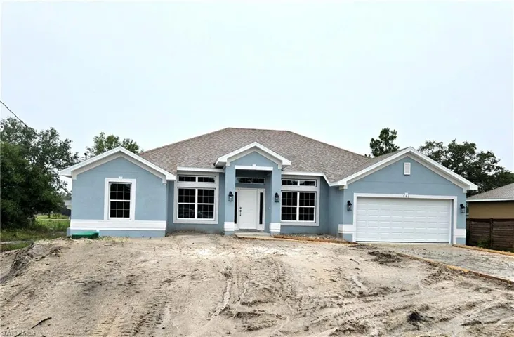 View of front facade with stucco siding, a garage, roof with shingles, and driveway