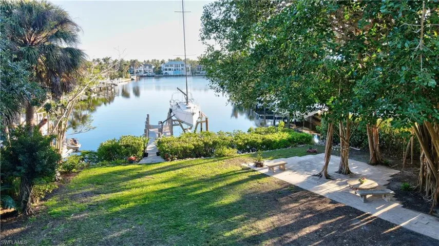 View of green lawn with boat lift, a dock, and a water view