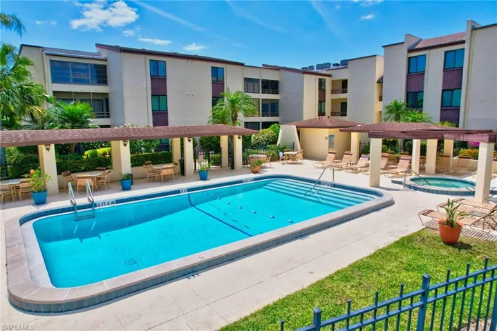 Pool with a community hot tub, a pergola, a patio, and fence