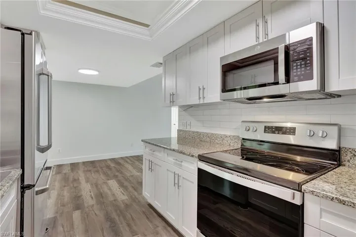 Kitchen with a raised ceiling, visible vents, ornamental molding, decorative backsplash, and appliances with stainless steel finishes