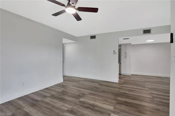 Unfurnished room with baseboards, visible vents, a ceiling fan, and dark wood-style floors