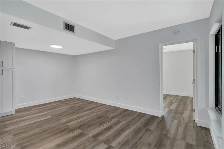 Spare room featuring baseboards, wood finished floors, and visible vents