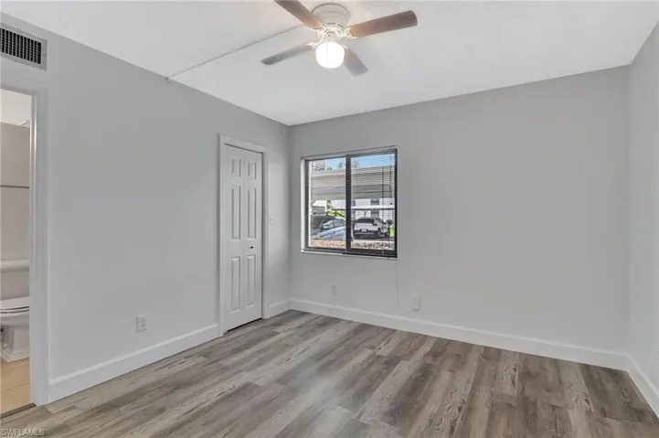 Unfurnished bedroom featuring baseboards, wood finished floors, visible vents, and a closet