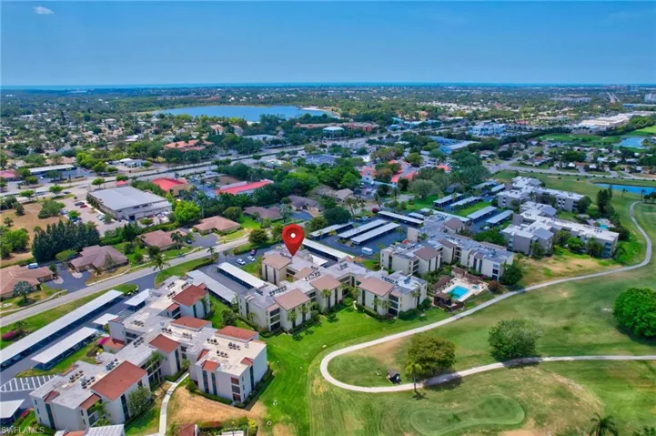 Drone / aerial view with golf course view, a water view, and a residential view