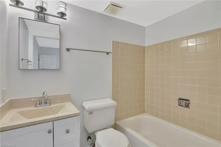 Bathroom with visible vents, toilet, vanity, and shower / washtub combination
