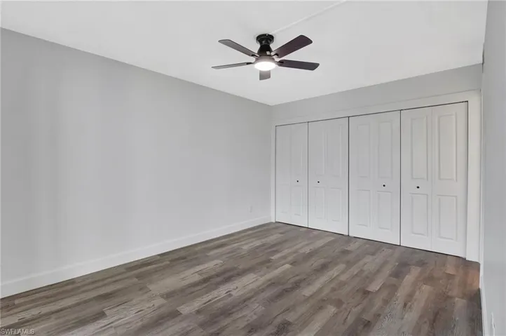 Unfurnished bedroom with wood finished floors, a closet, baseboards, and ceiling fan