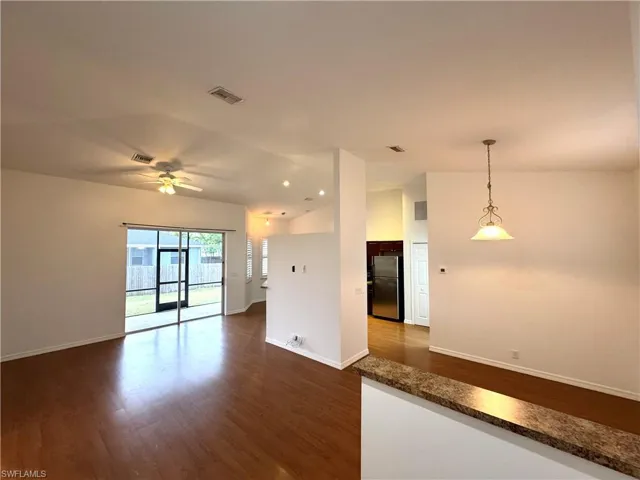 Unfurnished room with vaulted ceiling, ceiling fan, and dark hardwood / wood-style flooring
