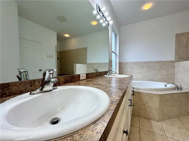 Bathroom featuring shower with separate bathtub, vanity, and tile patterned flooring